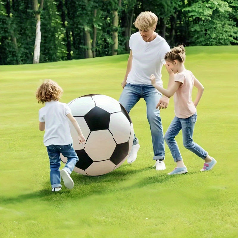 Familie der spiller med kæmpefodbolden på græsplænen